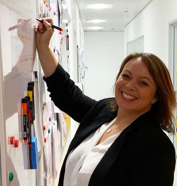 Lady smiling while writing on whiteboard