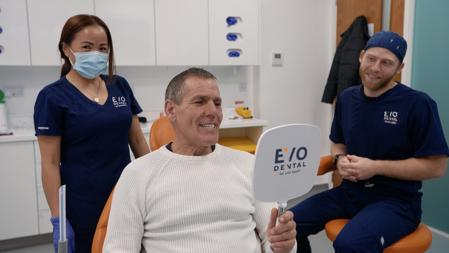 Man smiling while looking at his new smile in the mirror